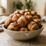 A pile of golden-brown sourdough pretzel bites sprinkled with coarse salt, served in a rustic bowl.